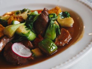 Close-up of a savory Asian stir-fry with assorted vegetables and meat, garnished with sauce.