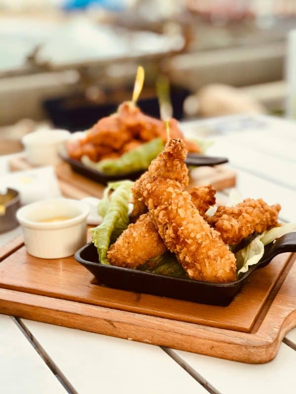 Delicious crispy chicken strips served with a side of sauce on a wooden board.